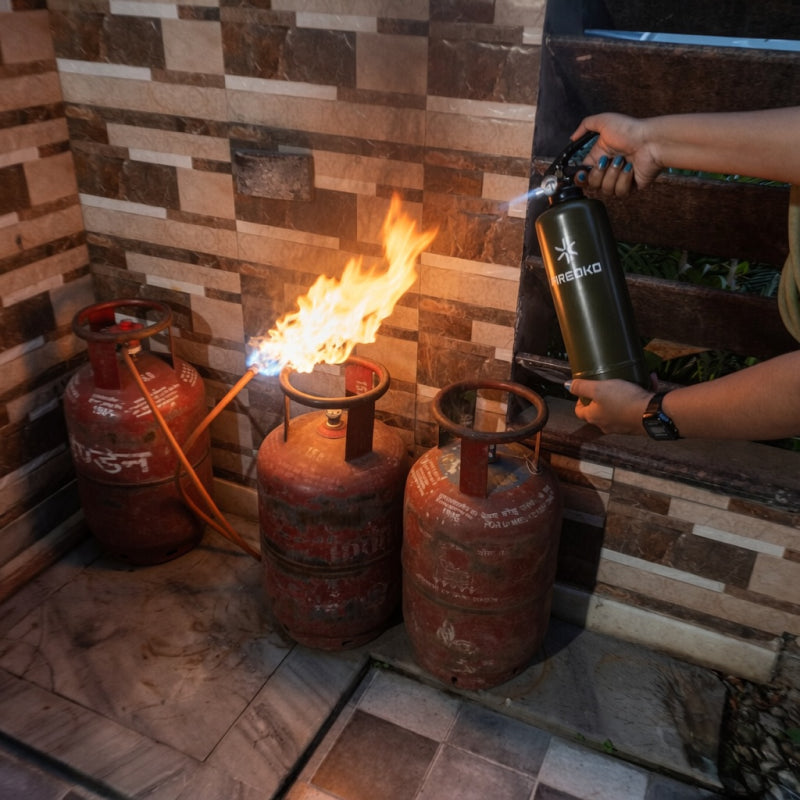 Person using a Fireoko fire extinguisher to control a flame coming from a kitchen gas cylinder in a home setting
